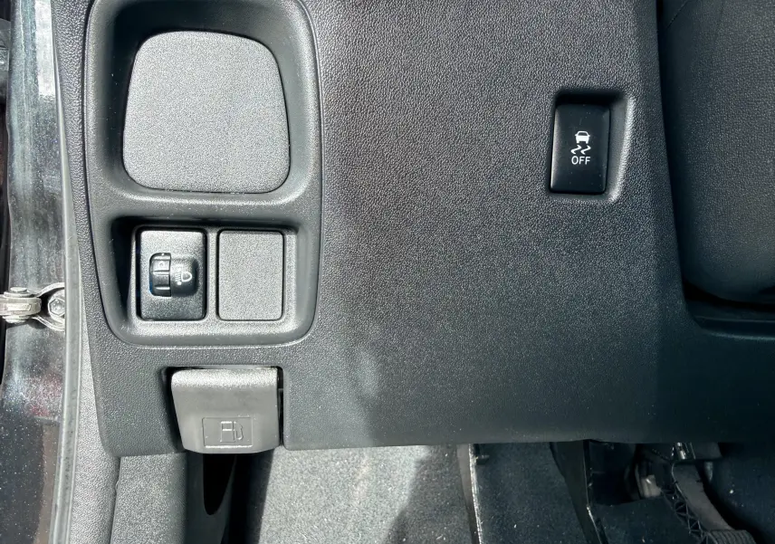 Détail du tableau de bord côté gauche d'une Peugeot 108 noire, montrant les commandes d'éclairage et le bouton de désactivation de l'ESP.