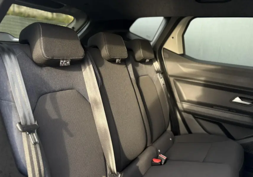 Vue intérieure côté droit sur la banquette arrière noire du Dacia Duster 2024 Beige Sandstone avec ceinture de sécurité.