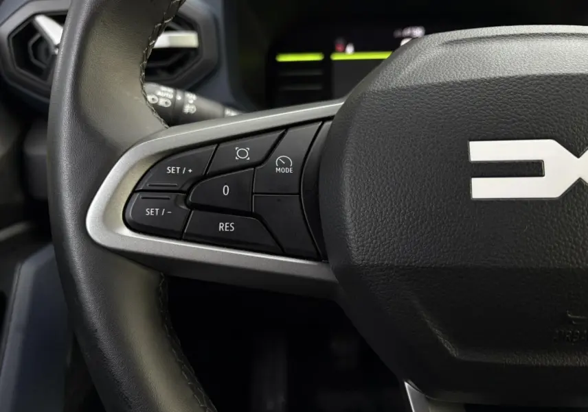 Gros plan sur les commandes au volant à gauche du Dacia Duster 2024 beige Sandstone, version ECO-G 100 Journey.