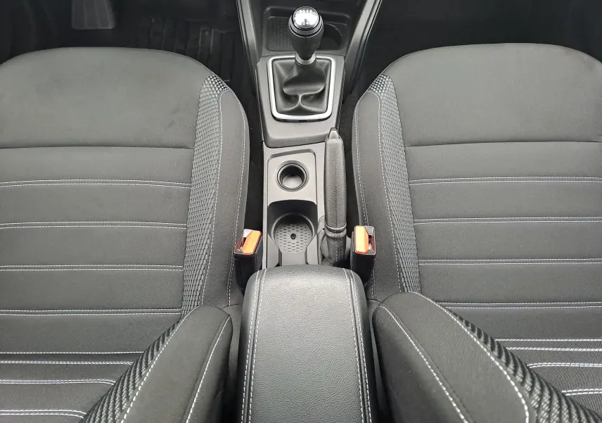 Vue plongeante sur l'intérieur noir du Dacia Duster 2023, montrant la console centrale avec levier de vitesses manuel et accoudoir.