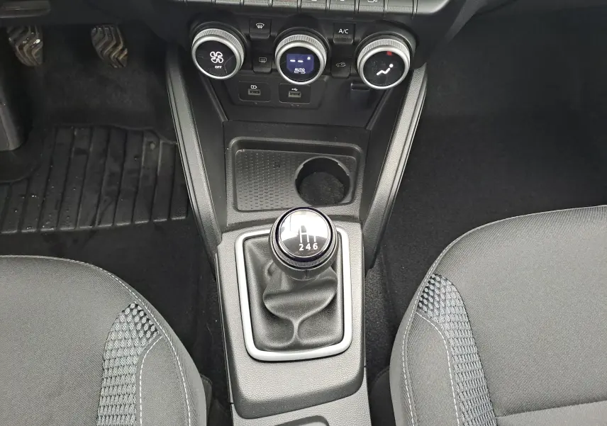 Vue plongeante sur la console centrale du Dacia Duster 2023, avec levier de vitesse manuel et sièges tissu noir.