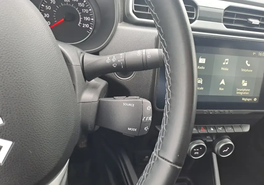 Vue rapprochée de l’intérieur du Dacia Duster 2023, volant noir et écran tactile avec menu multimédia visible.