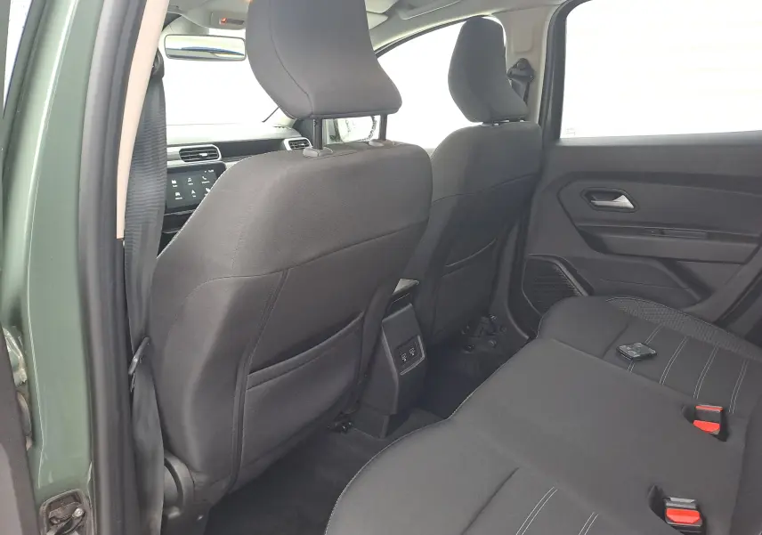 Vue intérieure arrière côté gauche du Dacia Duster 2023 kaki, montrant les sièges noirs et la console centrale avec ports USB.
