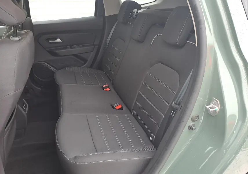 Vue intérieure côté gauche montrant la banquette arrière noire du Dacia Duster 2023 en couleur kaki Liken.