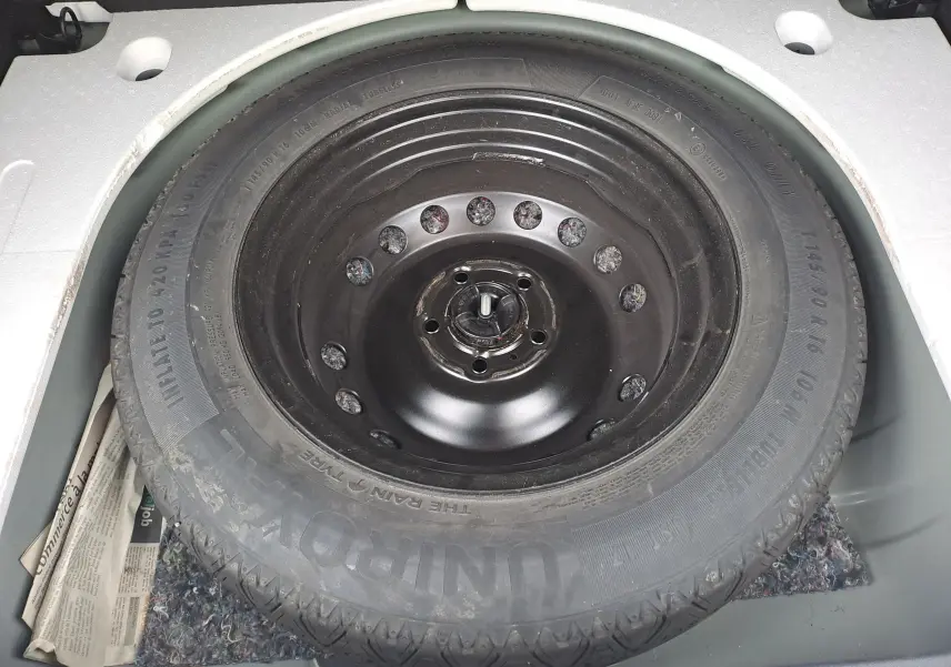 Pneu de secours noir monté dans le coffre d'un Dacia Duster 2023, version 1.5 BlueDCI 115 Journey kaki.