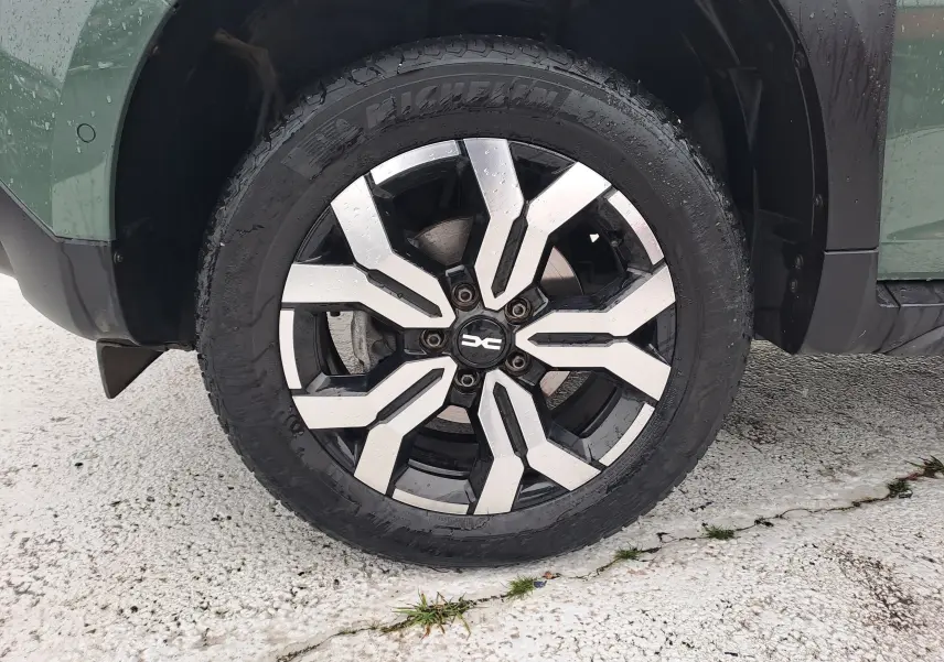 Gros plan sur la roue avant gauche du Dacia Duster kaki Liken 2023 avec jante alliage bicolore au design moderne.