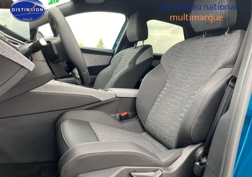 Vue intérieure côté conducteur du Peugeot 3008 bleu 2025, sièges tissu et cuir gris avec accoudoir central.