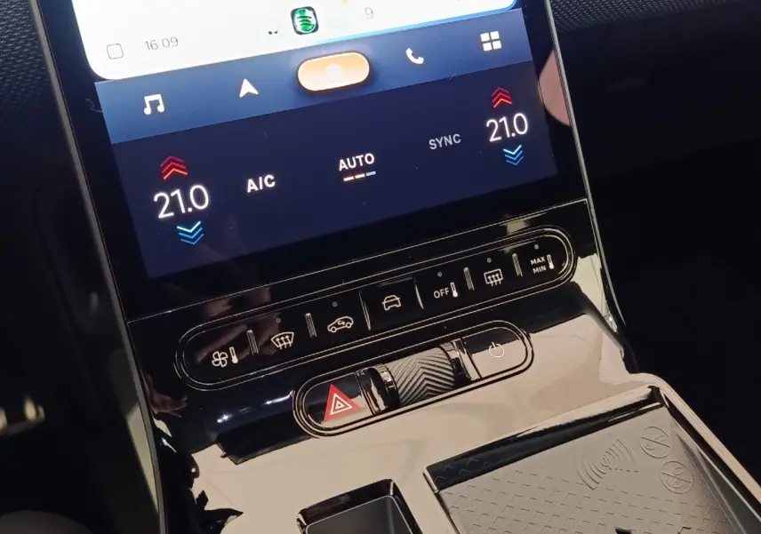 Gros plan sur la console centrale tactile noire du Citroën C5 hybride avec commandes climatisation et recharge sans fil.