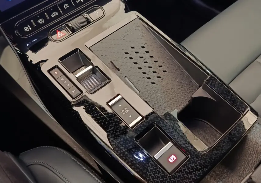 Gros plan sur la console centrale noire brillante de la Citroën C5 Hybride avec commandes de boîte auto et zone de recharge.