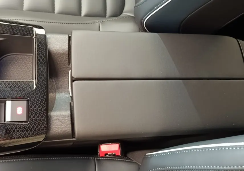 Détail de l'accoudoir central noir et console avec bouton frein électrique dans l'habitacle d'une Citroën C5 Hybride.