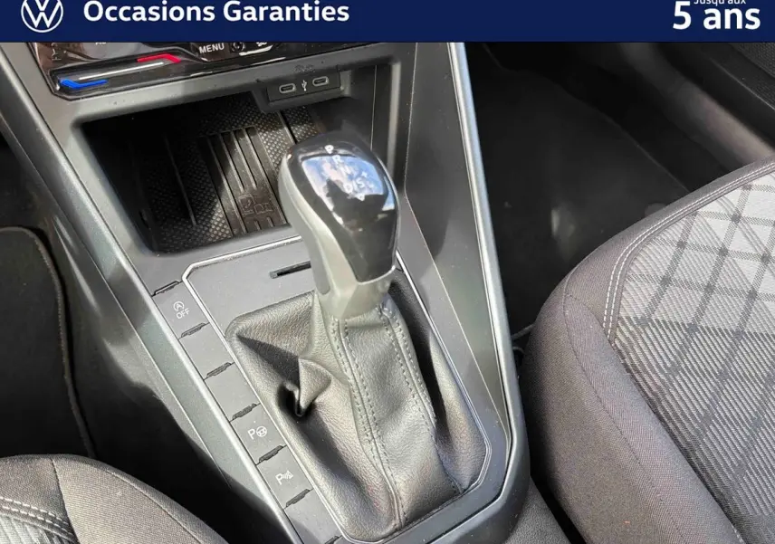 Levier de vitesse DSG7 en gros plan avec console centrale et siège avant droit tissu gris à motifs.
