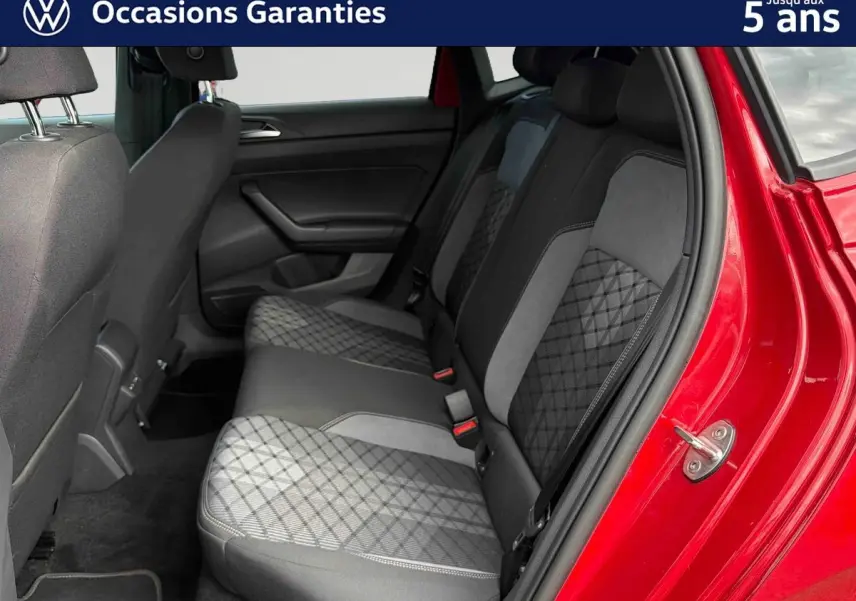 Vue intérieure côté arrière droit de la Volkswagen Polo rouge 2025, montrant la banquette arrière en tissu gris et noir.