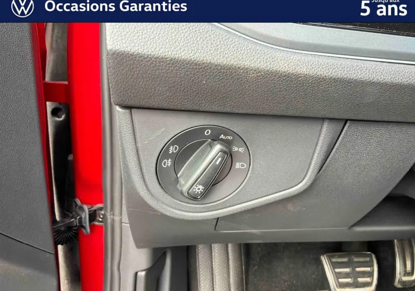 Détail de la commande d’éclairage sur le tableau de bord côté gauche d’une Volkswagen Polo rouge 2025.