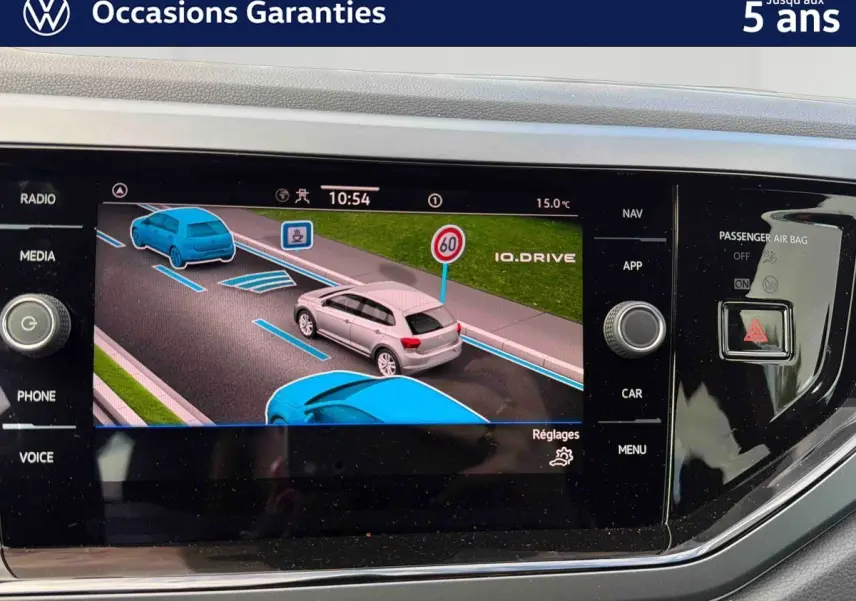Écran tactile central montrant l’assistance à la conduite avec véhicule gris en vue 3/4 arrière dans une Polo 2025 rouge.