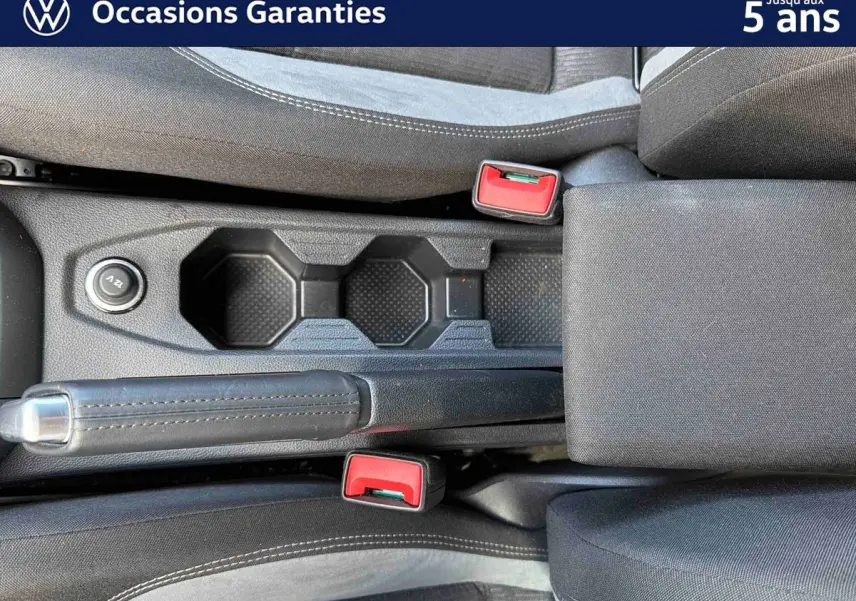 Vue rapprochée de la console centrale noire avec frein à main et deux ceintures rouges dans l’habitacle d’une Volkswagen Polo.