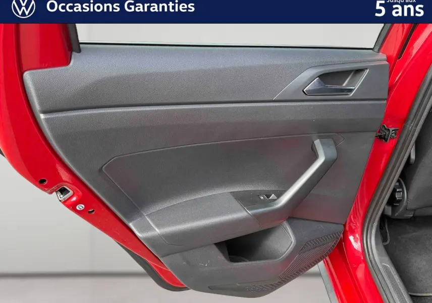 Vue rapprochée de la porte arrière gauche rouge métallisée d'une Volkswagen Polo 2025 avec garniture intérieure noire.