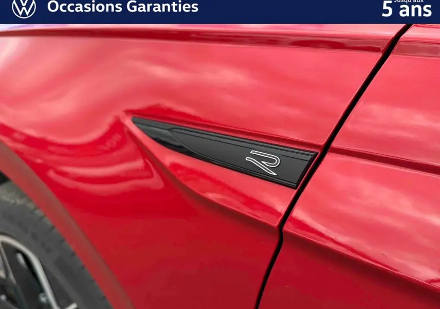 Détail de l'aile avant gauche rouge métallisée de la Volkswagen Polo 2025 avec logo R noir et jante alliage visible.