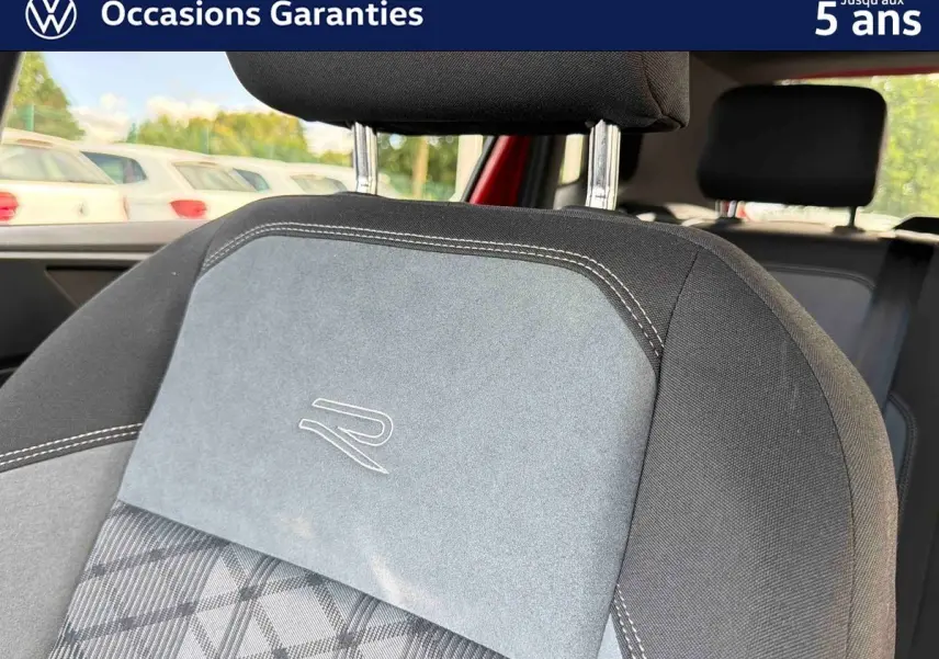 Gros plan sur le siège avant gris et noir avec logo "R" brodé, intérieur d'une Volkswagen Polo rouge.