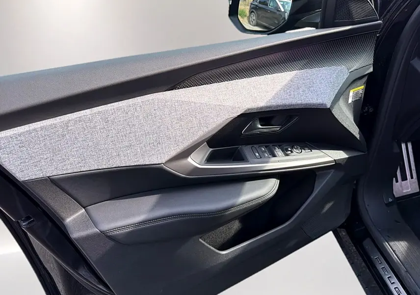 Vue intérieure côté gauche de la porte avant noire du Peugeot 5008 Hybrid 145 GT avec habillage tissu gris et commandes électriques.