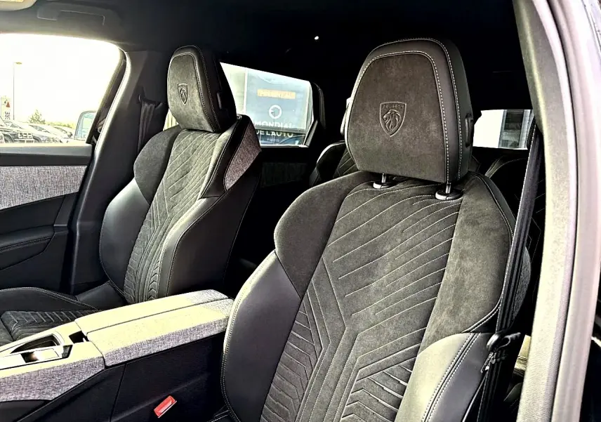 Vue intérieure rapprochée des sièges avant noirs en cuir et alcantara avec logo Peugeot embossé sur les appuie-têtes.