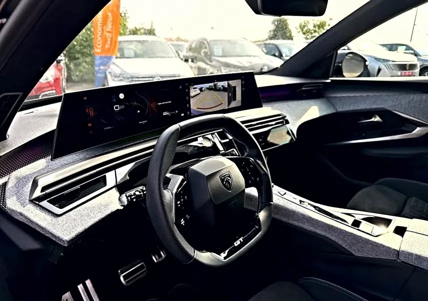 Intérieur du Peugeot 5008 Hybrid 145 GT 2025, vue côté conducteur sur le tableau de bord et volant cuir noir.
