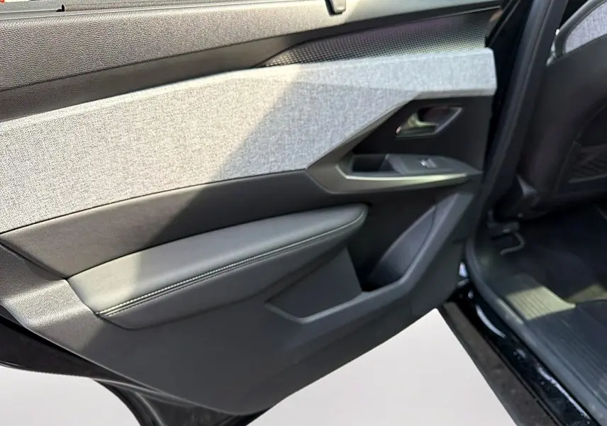 Vue rapprochée de la porte arrière droite noire du Peugeot 5008 Hybrid 145 GT, avec garniture tissu et cuir gris.