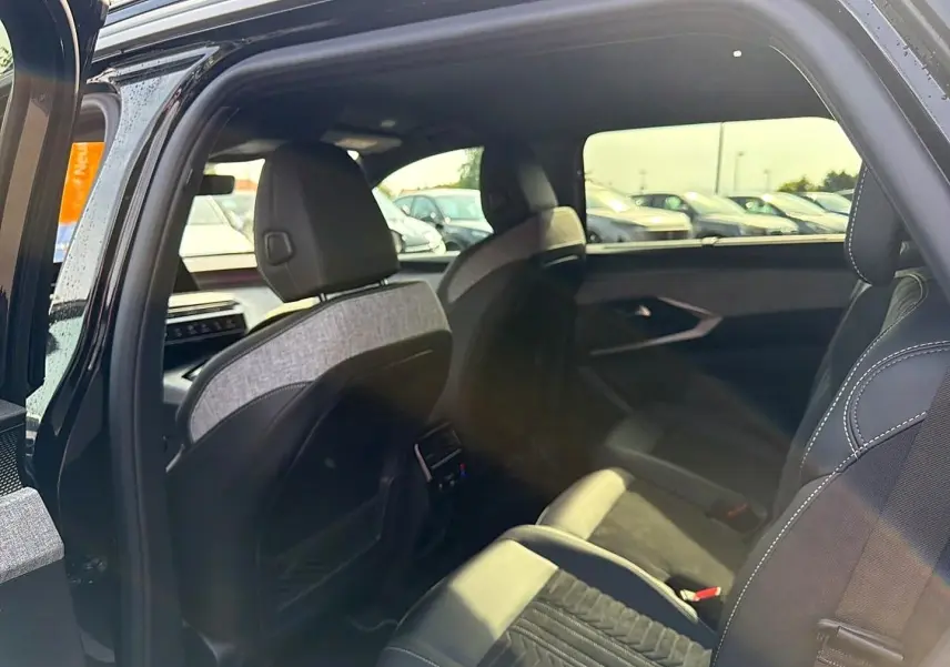 Vue intérieure côté droit du Peugeot 5008 Hybrid 145 GT 2025 noir, montrant les sièges arrière et détails de la porte ouverte.