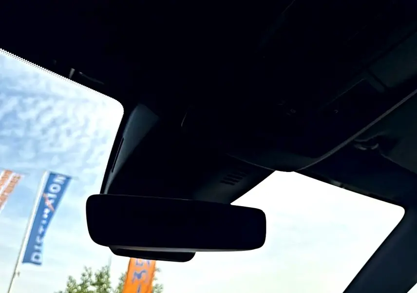 Vue intérieure du rétroviseur central d'un Peugeot 5008 noir, avec ciel et drapeaux visibles à l'extérieur.