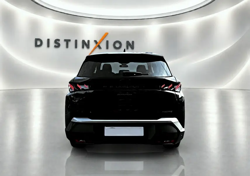 Vue arrière d'un Peugeot 5008 Hybrid 145 GT noir, avec feux arrière LED et becquet distinctif dans un showroom lumineux.