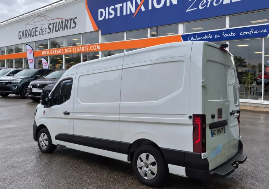 Renault Master blanc vu en 3/4 arrière droit, fourgon L2H2 avec feux arrière LED distinctifs, stationné devant un garage.