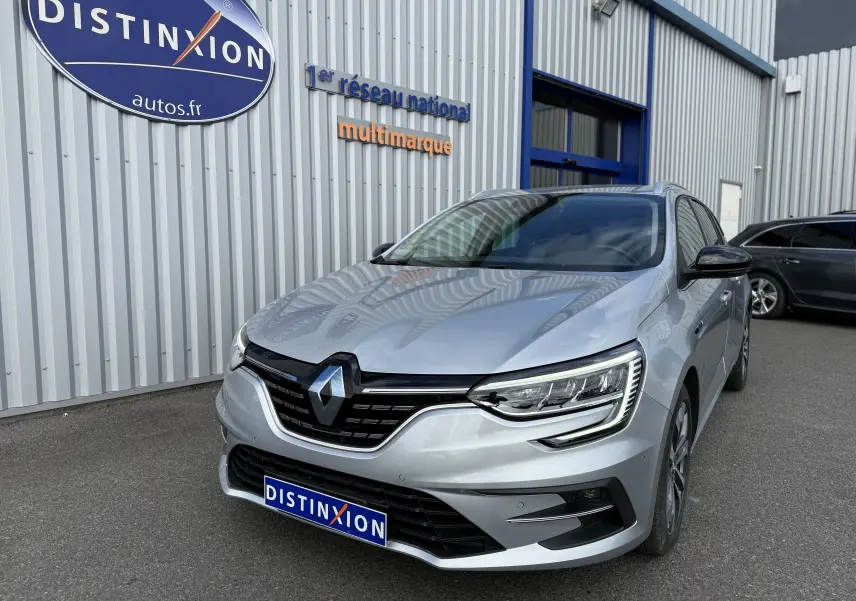 Renault Mégane Break gris Highland Metal vue 3/4 avant droit, avec calandre noire et phares LED distinctifs.
