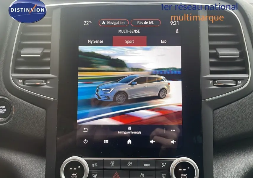 Écran tactile intérieur montrant une Renault Mégane Break gris Highland en mode Sport sur circuit, vue latérale droite.