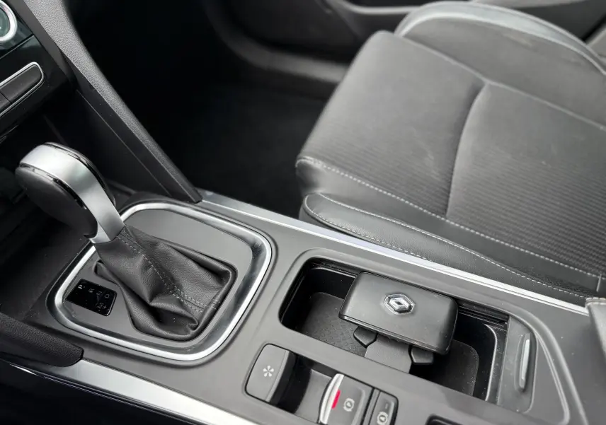 Gros plan sur la console centrale de la Renault Mégane Break 2024 avec levier de boîte auto et clé grise Highland Metal.
