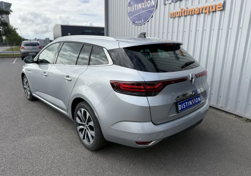 Vue 3/4 arrière droite d'une Renault Mégane Break gris Highland Metal avec feux arrière LED et toit noir brillant.