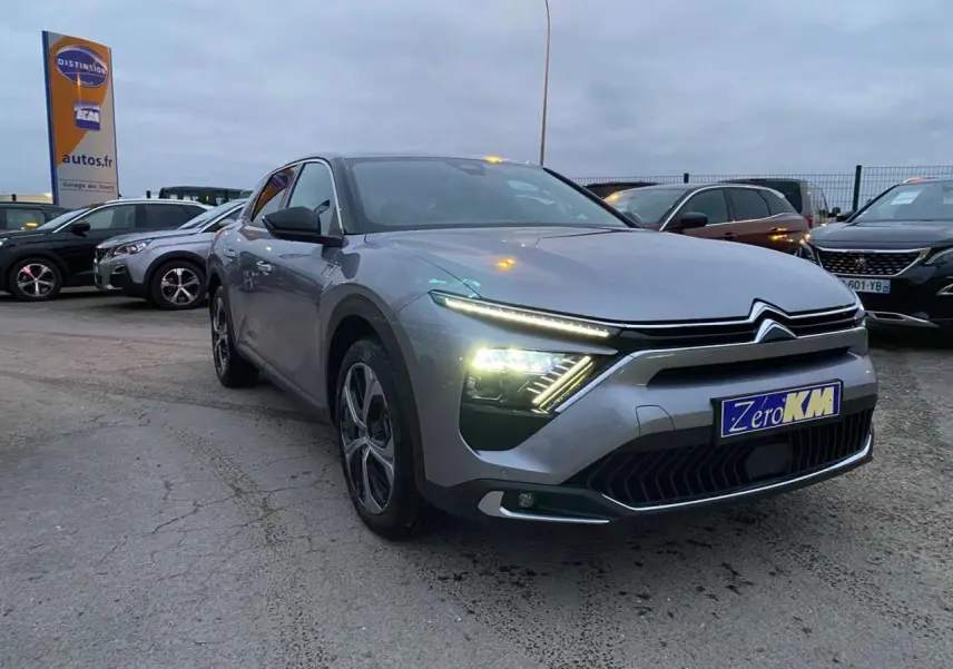 Citroën C5 X gris Artense métal en 3/4 avant droit avec phares LED allumés sur parking extérieur.