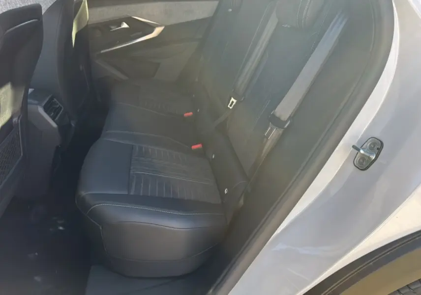 Vue côté droit de l'habitacle arrière du Peugeot 3008 Hybrid 136 GT Plus blanc okénite avec sièges noirs en cuir et tissu.