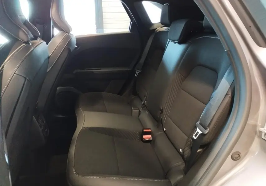 Vue intérieure arrière côté droit du Renault SYMBIOZ 2025, sièges tissu noir avec surpiqûres blanches, portière gris cassiope visible.