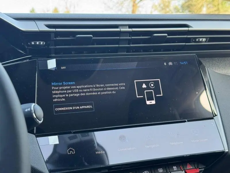 Vue rapprochée de l’écran tactile central noir de la Peugeot 308 blanc Okénite, affichant la fonction Mirror Screen.