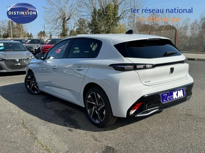 Vue 3/4 arrière droite d'une Peugeot 308 blanche Okénite avec feux arrière LED et jantes alliage noires.