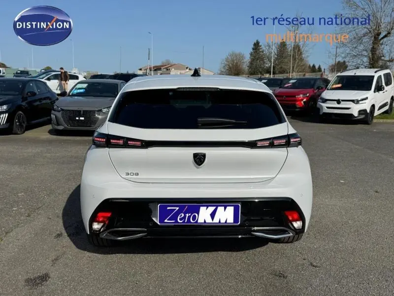 Vue arrière d'une Peugeot 308 blanche Okénite avec feux arrière LED et double sortie d'échappement chromée.