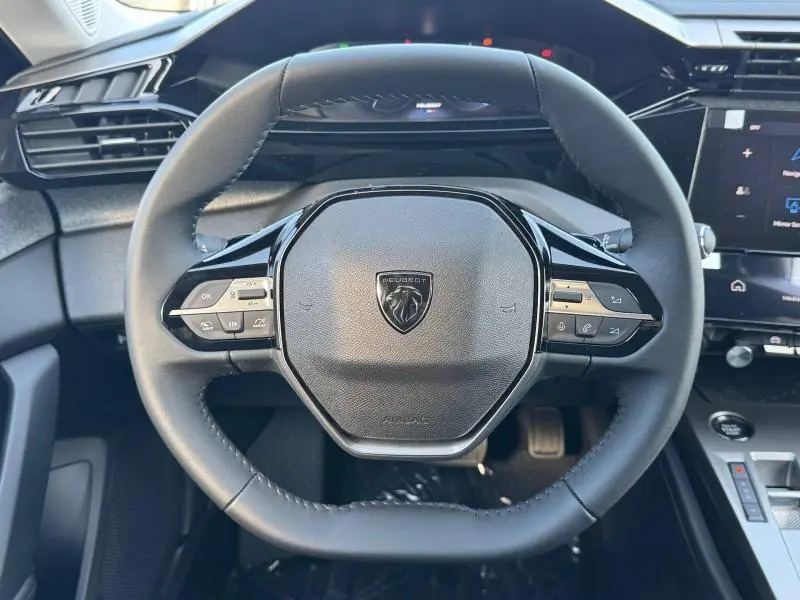 Vue rapprochée du volant noir multifonction de la Peugeot 308 2025 avec logo lion au centre et commandes intégrées.