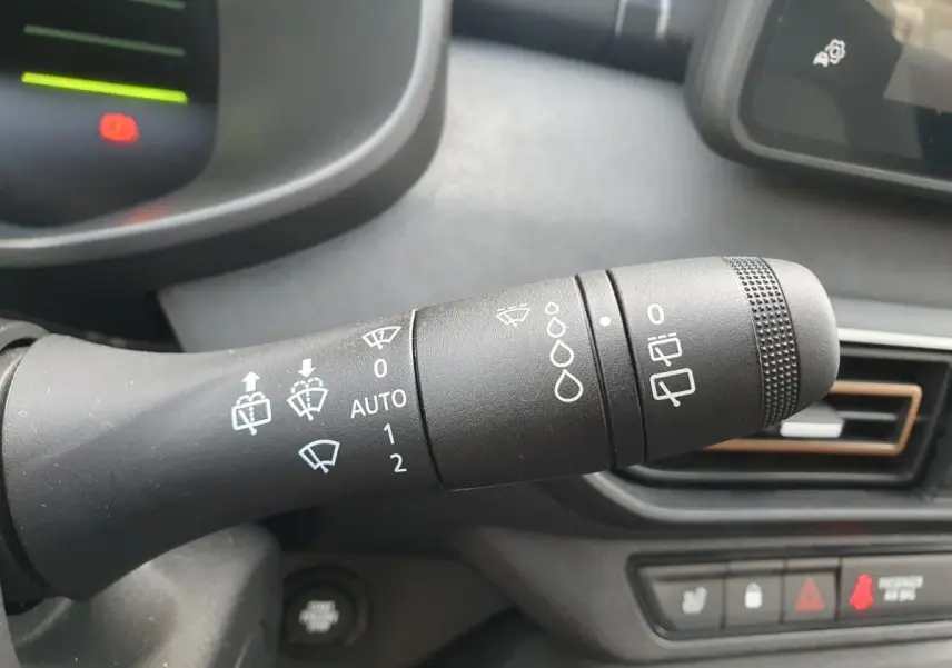 Gros plan sur la commande des essuie-glaces dans l’habitacle du Dacia Jogger vert cèdre, tableau de bord en arrière-plan.