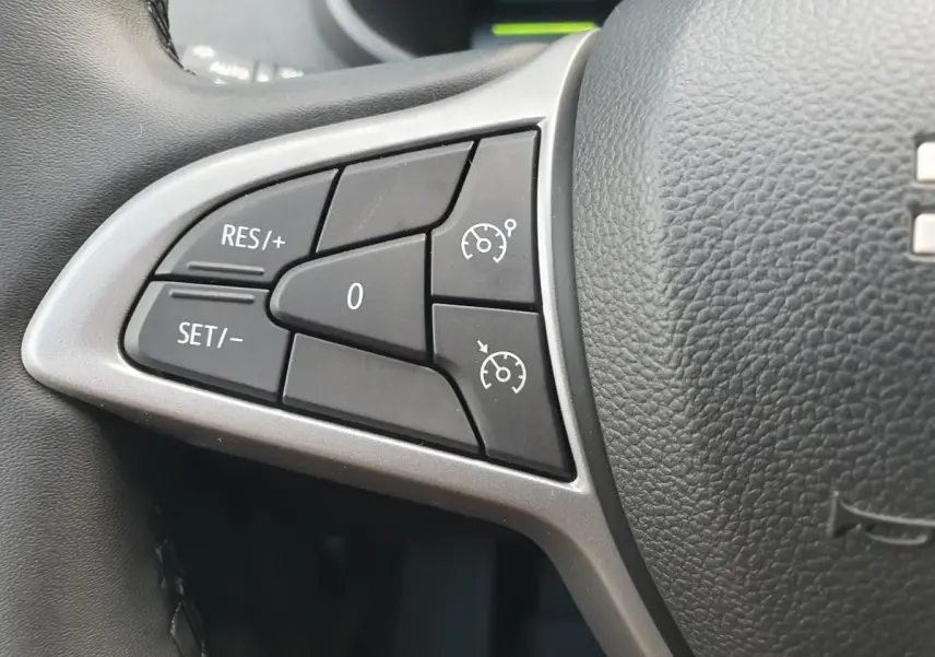 Gros plan sur les commandes de régulateur de vitesse à gauche du volant du Dacia Jogger 2026, intérieur noir.
