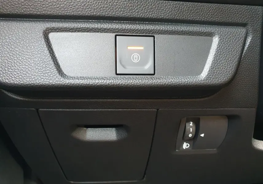 Détail intérieur du tableau de bord du Dacia Jogger 2026, bouton de verrouillage centralisé et réglage des phares.