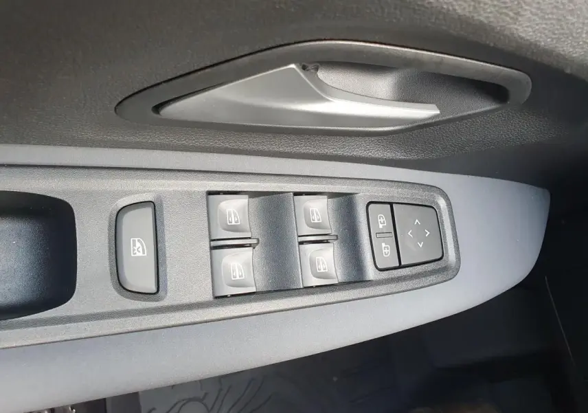 Vue rapprochée des commandes des vitres et rétroviseurs sur la porte côté conducteur d’un Dacia Jogger vert cèdre.