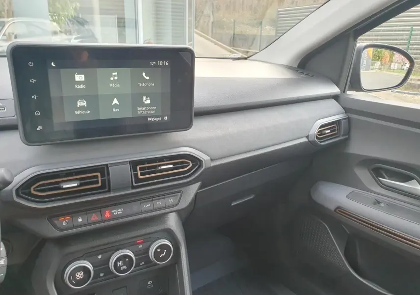 Vue intérieure côté passager du tableau de bord et écran tactile du Dacia Jogger 1.6 Hybrid 2026 avec finitions noires et détails cuivre.