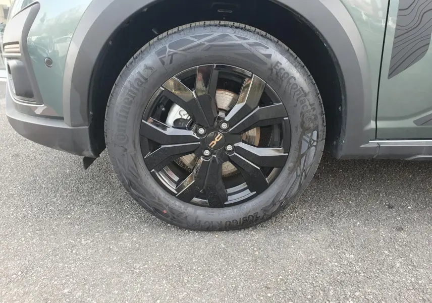 Gros plan sur la roue avant droite noire avec jante aluminium 16” Mahalia du Dacia Jogger vert cèdre.