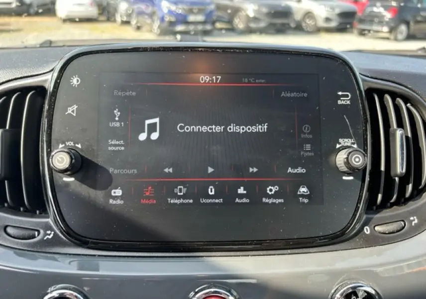 Écran tactile central du tableau de bord de la Fiat 500C gris/rouge, affichant le menu audio et connectivité.