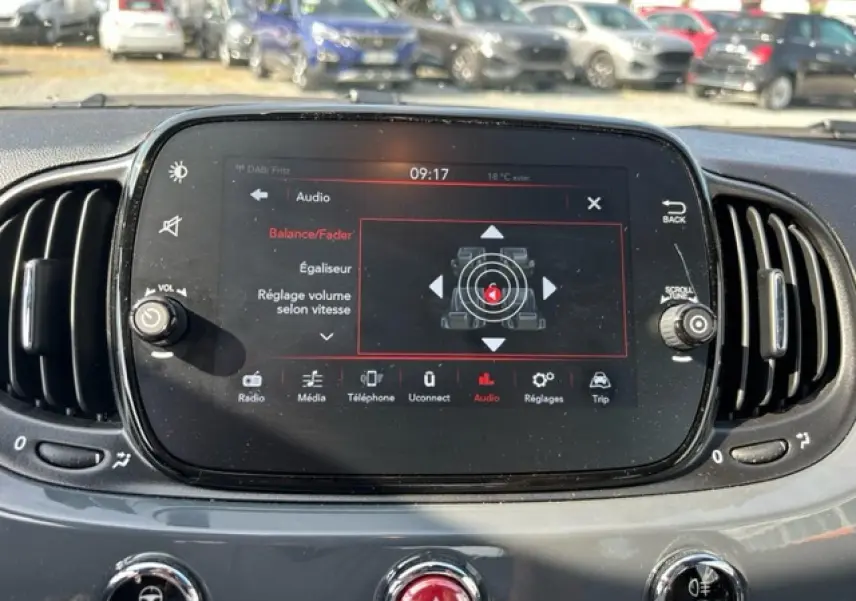 Écran tactile central du tableau de bord de la Fiat 500C 2021, affichant les réglages audio avec commandes autour.