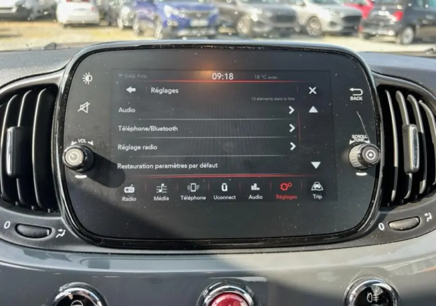 Écran tactile central du tableau de bord de la Fiat 500C gris/rouge, affichant le menu Réglages en plein jour.